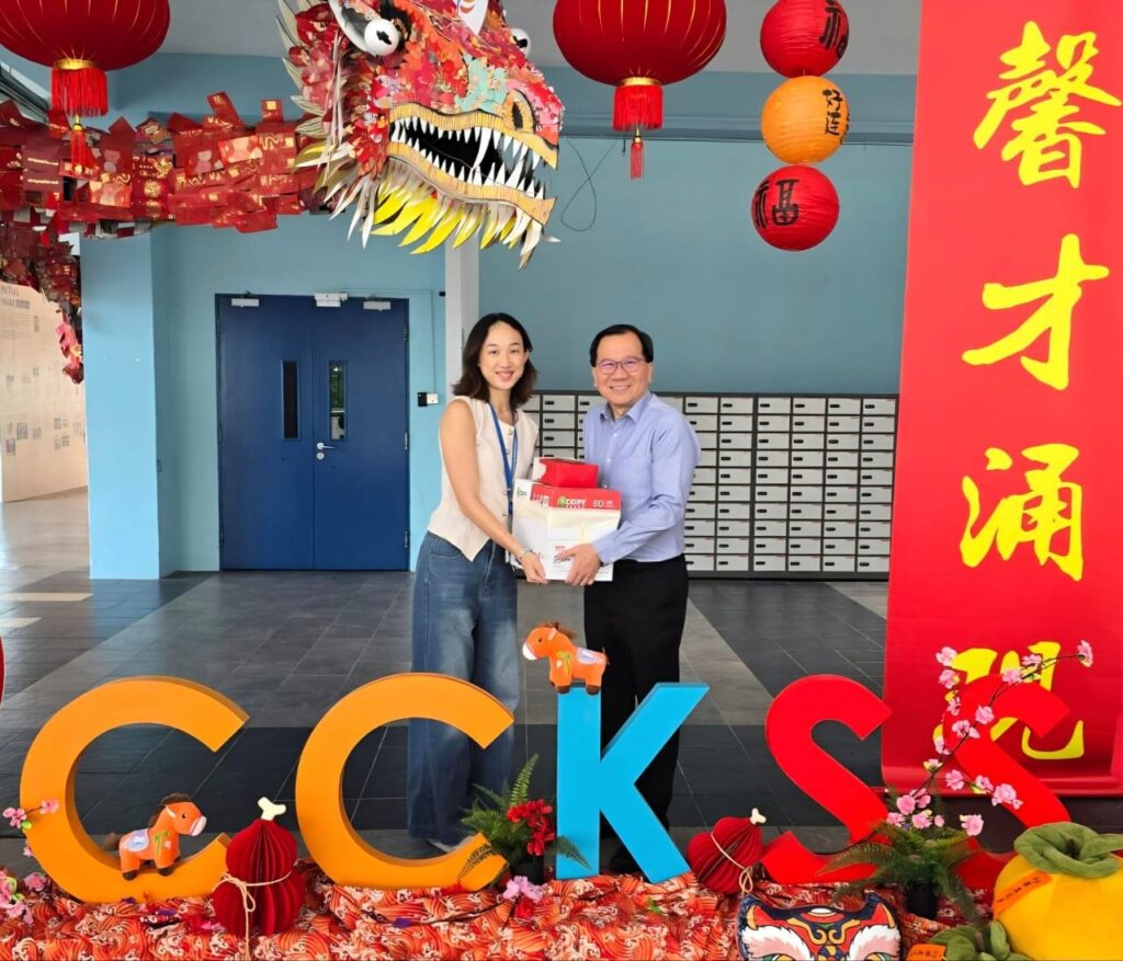 An MWS representative receiving the donations from Chua Chu Kang Secondary School Principal Timothy Cheng.