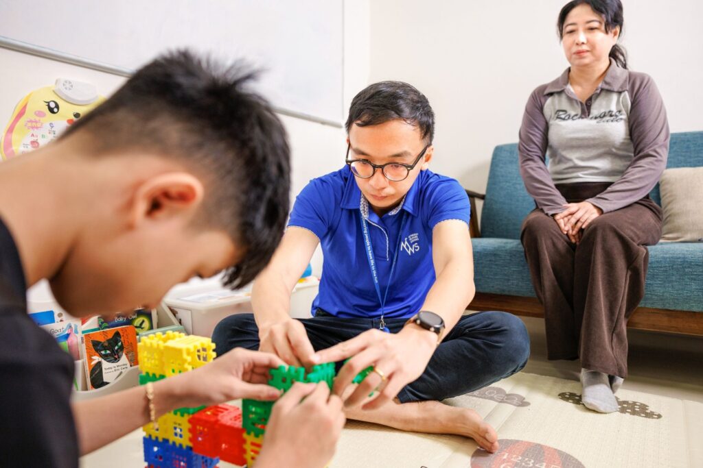 Edwin engaging with Minh* as his mother, Thi Loi, looks on