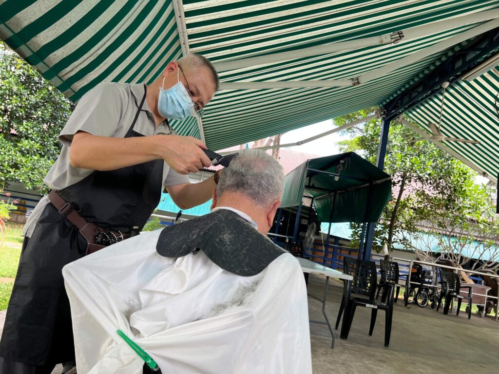 Alvin Foo trimming the hair of a nursing home resident.